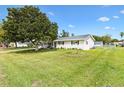 Well-manicured lawn surrounds a charming one-story home with lush landscaping, a cozy porch, and a flagpole at 10385 Se 178Th St, Summerfield, FL 34491