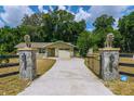 Gated entrance with lion statues on stone pillars leading to the house at 13300 Ne 38Th Ave, Anthony, FL 32617