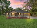 Inviting home with manicured lawn, front yard seating, and warm lighting creating a cozy ambiance at 16 Northern Dancer Dr, Ocala, FL 34482