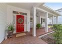 Inviting front porch with a red door, rocking chair, and brick tile flooring at 1910 Se 28Th Pl, Ocala, FL 34471