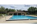 Community pool area surrounded by lush landscaping, sun loungers, and shaded seating at 501 Fairways Ln # A, Ocala, FL 34472