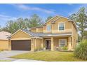 Tan two-story home featuring a large driveway, well-kept lawn, and mature trees at 5781 Sw 39Th St, Ocala, FL 34474