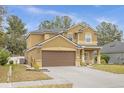 Side view of a tan two-story home featuring a large driveway, well-kept lawn, and mature trees at 5781 Sw 39Th St, Ocala, FL 34474