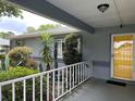 Inviting front porch with a charming yellow door and lush landscaping at 6082 Sw 104Th St, Ocala, FL 34476