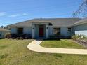 Inviting home exterior with green lawn and walkway leading to the red front door at 6134 Sw 155Th Street Road, Ocala, FL 34473