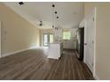 Open-concept living room with wood-look flooring, ceiling fan, and island with pendant lighting at 13375 Se 42Nd Ave, Belleview, FL 34420