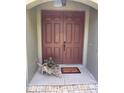 Charming entryway featuring double doors, a 'Welcome' mat, and a decorative planter, creating a warm invitation at 35 Lake Wood Cir, Ocala, FL 34482