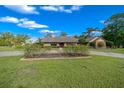 Lovely home featuring lush landscaping, a sprawling lawn, and charming architectural details under a bright blue sky at 5950 Sw 21St Avenue Rd, Ocala, FL 34471