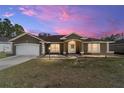 Charming single-story home with a manicured lawn and a two-car garage under a beautiful sunset at 13361 Sw 88Th Ter, Ocala, FL 34473