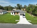 Aerial view of a modern home with a well-maintained lawn, long driveway, and a car parked in front at 11555 Sw 59Th Ter, Ocala, FL 34476
