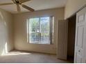 Bright bedroom with neutral carpet, a ceiling fan, and a large window providing natural light at 1703 Sanderling St, The Villages, FL 32162