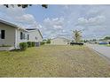 Spacious side yard showcasing the home's siding, manicured bushes, and lawn at 17475 Se 107Th Ct, Summerfield, FL 34491