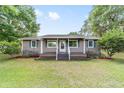 Inviting single-story home featuring a charming front porch, a well-manicured lawn, and lush green landscaping at 2720 Se 145Th St, Summerfield, FL 34491