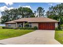 Charming home exterior with a well-manicured lawn and a grand, stained wood garage door at 5770 Sw 89Th Pl, Ocala, FL 34476