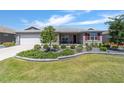 Inviting home with a well-manicured lawn, decorative shrubs, and a charming facade at 8820 Sw 104Th Cir, Ocala, FL 34481