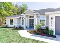 Charming home showcasing a landscaped front yard, gray paint, and a modern front door at 8878 Sw 133Rd Lane Rd, Ocala, FL 34473