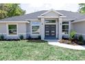 Lovely gray home that includes manicured lawn, garden bed, and a modern front door at 8878 Sw 133Rd Lane Rd, Ocala, FL 34473