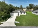 Aerial view of a modern white home featuring a long driveway and well-maintained green lawn at 11537 Sw 59Th Ter, Ocala, FL 34476