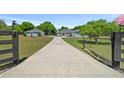Long driveway leads to a single-story home with a detached garage at 2563 Se 156Th Place Rd, Summerfield, FL 34491