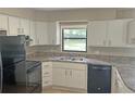 Functional kitchen with white cabinets, black appliances, and durable countertops at 1400 Ne 54Th St, Ocala, FL 34479