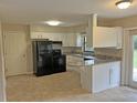 Well-lit kitchen with white cabinets, neutral countertops, and modern black appliances at 1400 Ne 54Th St, Ocala, FL 34479