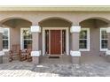 Inviting front porch with brick pavers, decorative columns, and comfortable seating creating a welcoming entrance at 5026 Sw 128Th St, Ocala, FL 34473