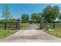 Long driveway leads to a gated entrance with stone pillars and black fencing, offering privacy at 5363 Nw 153Rd Ct, Morriston, FL 32668