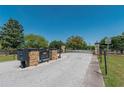 Community entrance gate with brick pillars, black metal fencing, and well-maintained landscaping at 5363 Nw 153Rd Ct, Morriston, FL 32668