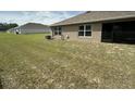 Spacious backyard featuring a well-maintained lawn, windows, and a sliding glass door at 7198 Sw 136Th Street Rd, Ocala, FL 34473