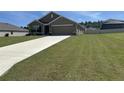 Charming single-story home featuring a well-manicured lawn and a long driveway leading to an attached garage at 7198 Sw 136Th Street Rd, Ocala, FL 34473
