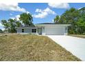 Charming single-story home featuring a two-car garage and a well-maintained lawn under a bright blue sky at 10435 Se 125 Ln, Belleview, FL 34420