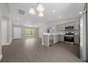 Open-concept kitchen featuring stainless steel appliances, quartz countertops, and wood-look flooring with natural light at 10435 Se 125 Ln, Belleview, FL 34420