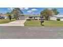 Inviting front yard featuring a driveway, green lawn, mature landscaping, and an attached two-car garage at 11118 Sw 76Th Ave, Ocala, FL 34476