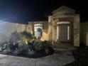 Well-lit home exterior at night showcases manicured landscaping, walkway, and illuminated entrance at 19939 Sw 96Th Pl, Dunnellon, FL 34432