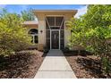 Covered front entryway with neutral colored siding and mature bushes on either side of the walkway at 21884 Sw 88Th Lane Rd, Dunnellon, FL 34431