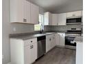 Bright kitchen with modern appliances, white cabinets, granite counters, and gray flooring at 5799 Sw 207Th Ct, Dunnellon, FL 34431