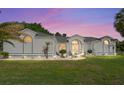 Inviting one-story home with well-maintained lawn, elegant landscaping, and a charming front entrance with arched windows at sunset at 5819 Ne 72Nd St, Silver Springs, FL 34488