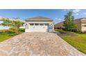 Two-car garage with brick paver driveway and well-maintained lawn at 9697 Sw 102Nd Ter, Ocala, FL 34481