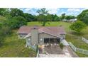 Back exterior of home has a covered screened-in porch, chimney, and a fenced yard with mature trees at 10575 Sw 27Th Ave, Ocala, FL 34476