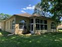 The rear exterior of a tan home featuring a sunroom with large windows and a door at 10918 Sw 71St Cir, Ocala, FL 34476