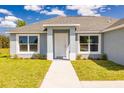 Inviting entryway featuring a white front door, manicured landscaping, and modern architectural details at 2329 Sw 143Rd Ct, Ocala, FL 34481
