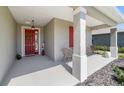 Cozy front porch featuring a red front door, seating area, and stylish columns at 10033 Sw 96Th St, Ocala, FL 34481