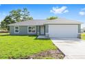 Charming home featuring a well-manicured lawn, large garage door, and beautiful stone accents at 10869 Sw 140Th Ave, Dunnellon, FL 34432