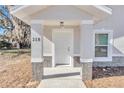 A close up of the clean white front door and porch with fresh paint and lighting fixture at 11415 Nw 15Th St, Ocala, FL 34482