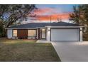 Charming home featuring a two-car garage, well-manicured lawn, and colorful sunset sky at 15854 Sw 38 Pl, Ocala, FL 34481
