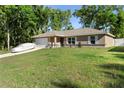 Well-maintained single-story home with lush lawn, attached garage, and covered vehicle in the driveway at 4243 Se 131St Ln, Belleview, FL 34420