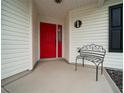 Cozy covered front porch featuring a vibrant red door and an ornamental bench at 882 Tanglewood Pl, The Villages, FL 32162