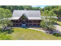 Aerial view of a charming log home with metal roof, surrounded by lush greenery and a well-maintained lawn at 3360 Se 183Rd Avenue Rd, Ocklawaha, FL 32179