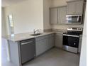 Modern kitchen featuring stainless steel appliances, gray cabinets, and granite countertops at 5077 Stokes Way, Wildwood, FL 34785
