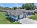 Angled view of the light blue one-story home, showcasing the two car garage and manicured front yard at 5350 Sw 82Nd St, Ocala, FL 34476
